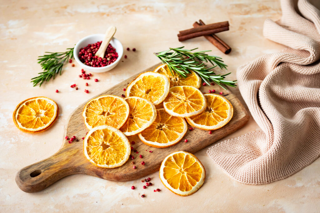 Getrocknete Orangenscheiben als Cocktail Garnitur mit Zimt und Rosmarin dekorativ angerichtet